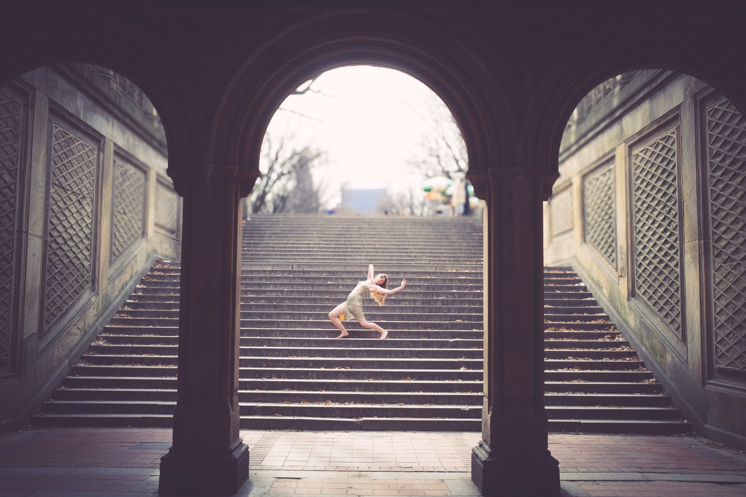 Dancer framed beneath architectural arches on stairs